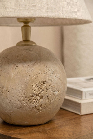 Marvexi table lamp – lifestyle shot on wooden side table beside a bouclé armchair, unlit, books stacked alongside, warm bedroom atmosphere