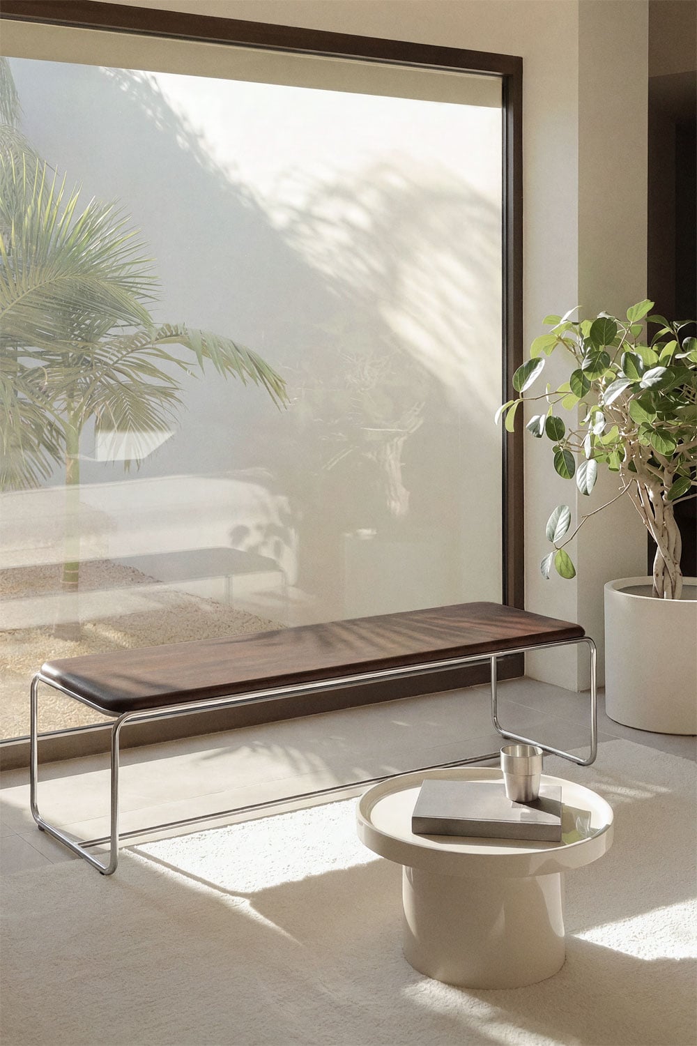Altrex bench – lifestyle shot by large window with plant, dark acacia wood and stainless steel frame