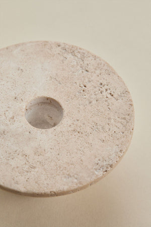 Bellvion travertine candle holder – close-up three-quarter view on beige background, no candle, showing the flared disc top and tapering cone base with fossilised pitting